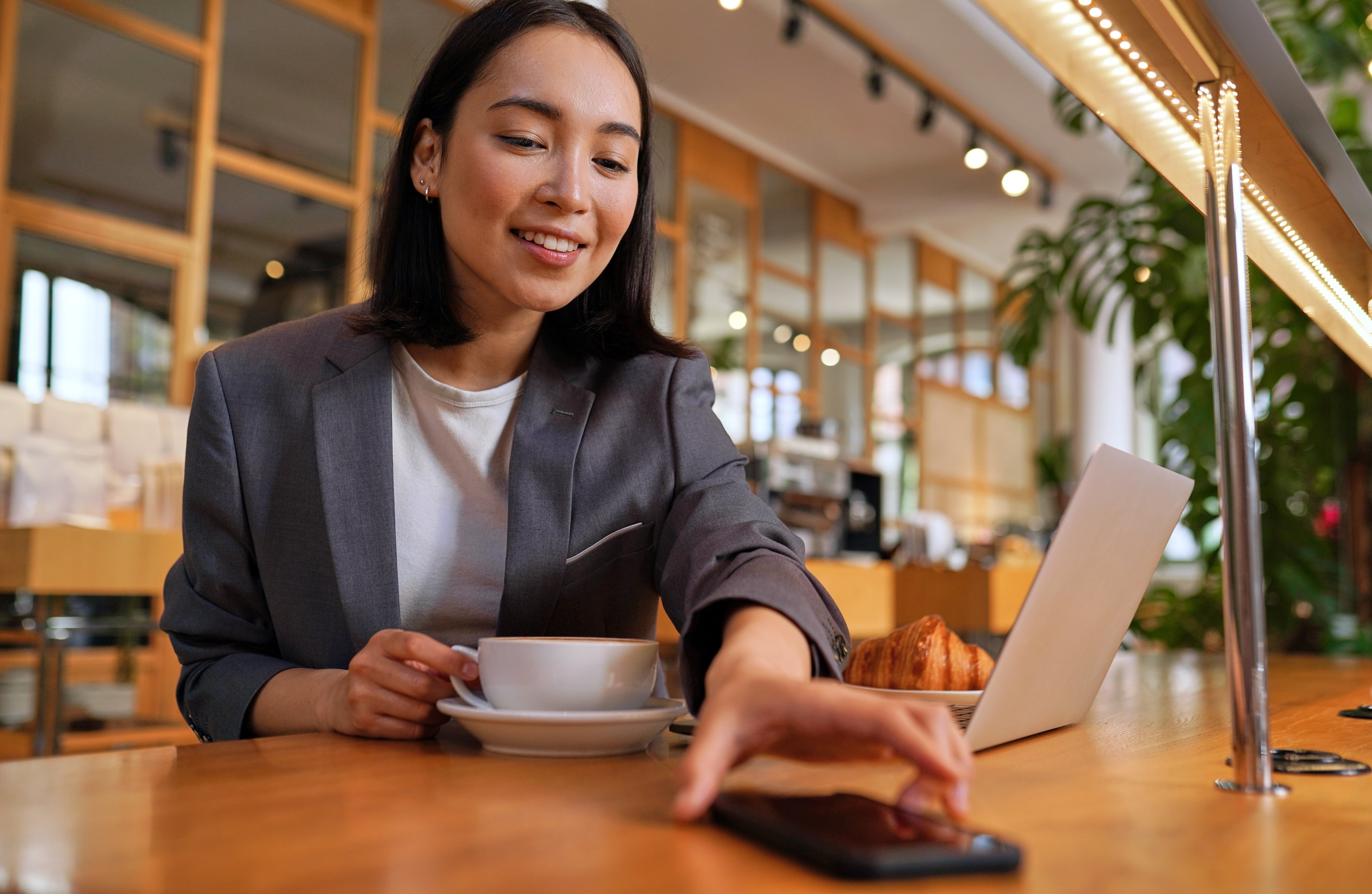 Business woman, reaching out for phone, drinking coffee.