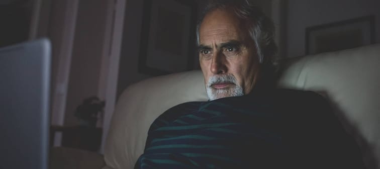 Older man looking at laptop in the dark