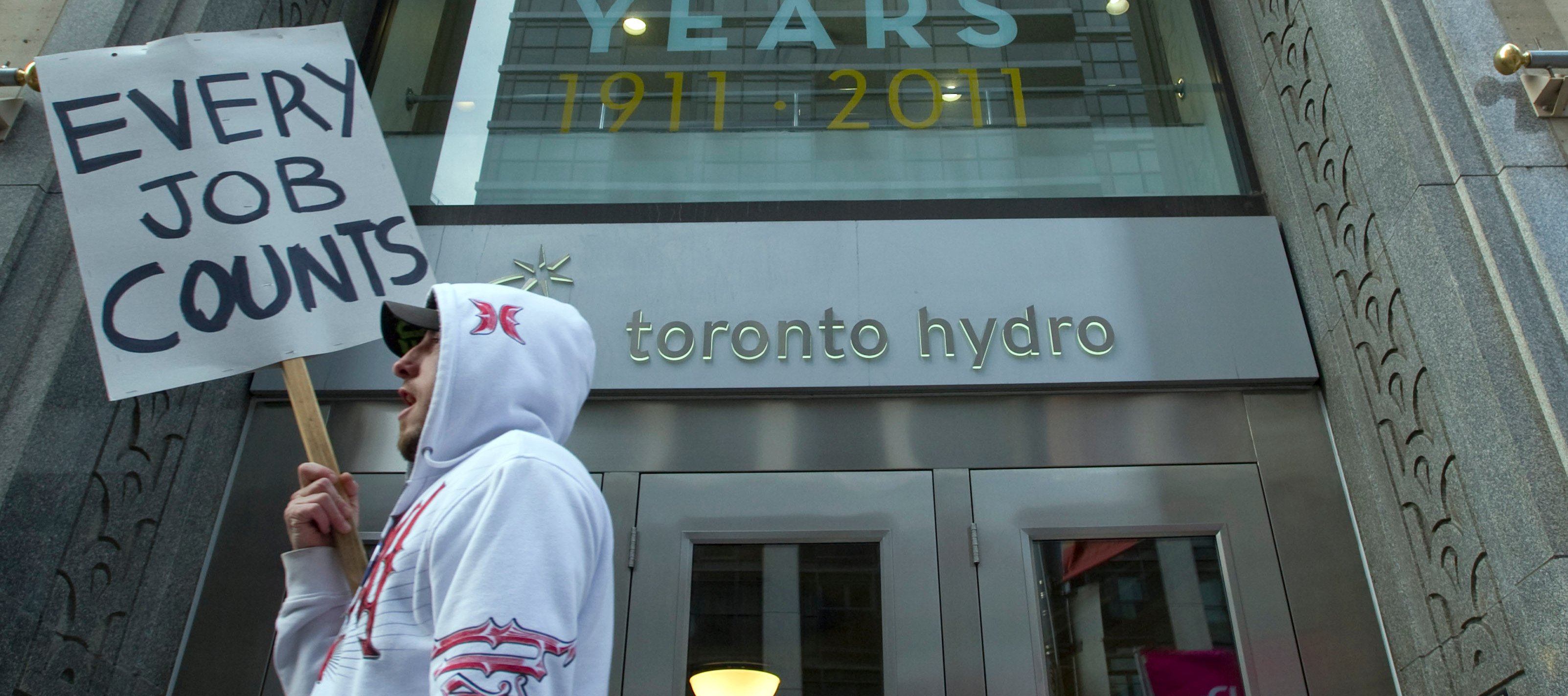 A protestor walks past the main doors of Toronto Hydro prior to impending layoffs. Feb 27, 2012.