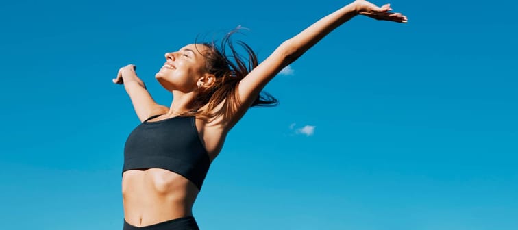 Young woman in fitness clothes smiling outside