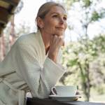 Older retired woman in dressing gown enjoying morning coffee