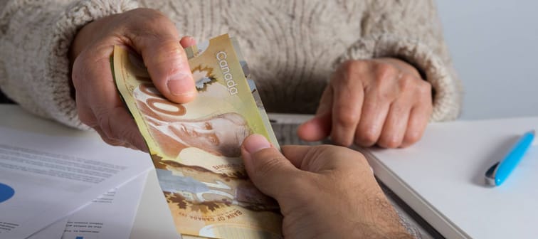 Middle aged woman handing over cash. Canadian currency