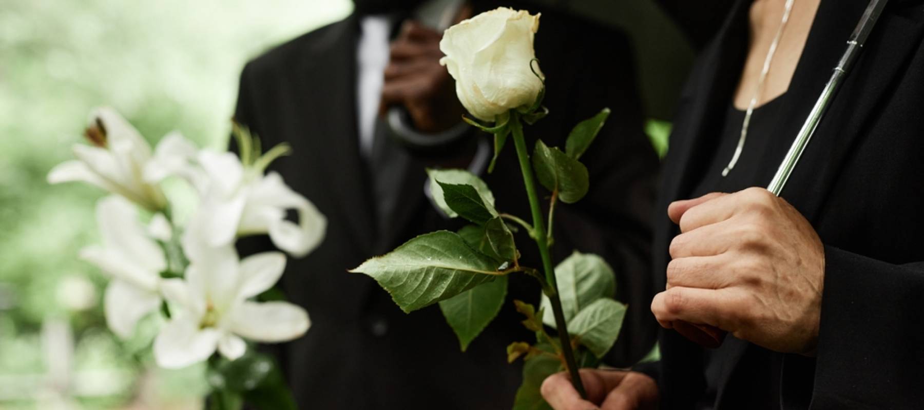 Close up of people holding roses at a funeral