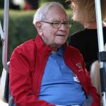 Chairman and CEO of Berkshire Hathaway Warren Buffett rides in a golf cart  + Greg Abel, chairman and CEO of Berkshire Hathaway Energy, walks with Andrea Abel
