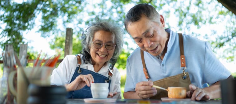 In the pottery workshop, an Asian retired couple is engaged in pottery making and clay painting activities.